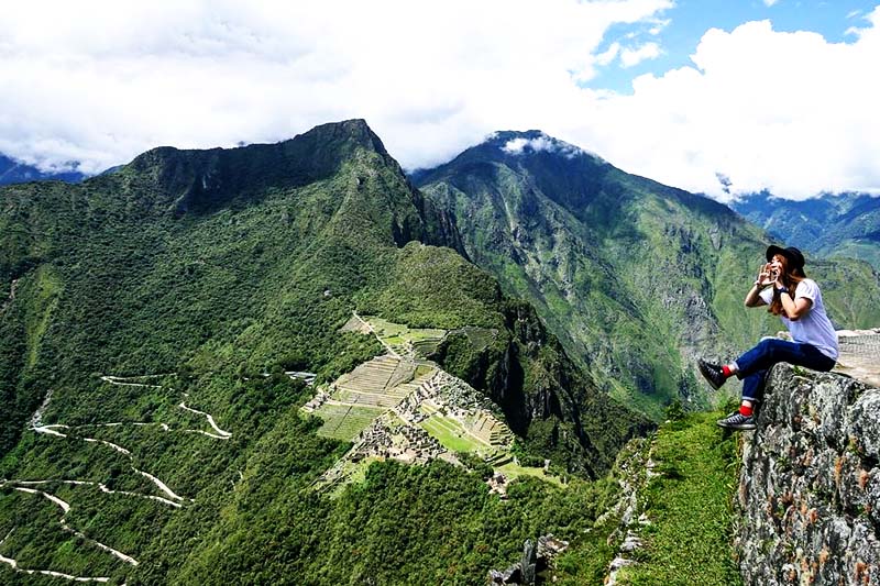Tourist sitting at the top of Huayna Picchu mountain