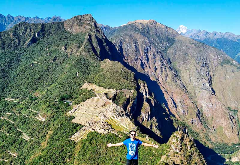 Tourist observing Machu Picchu from the top of Huayna Picchu mountain.